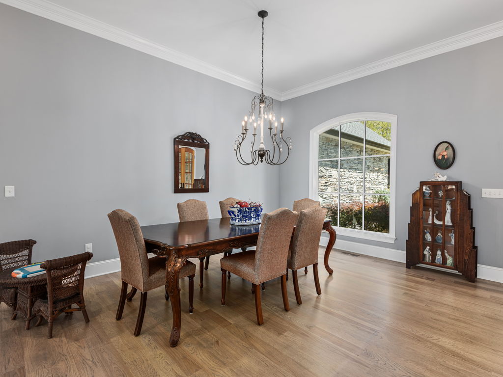 Formal dining room with warm hardwood floors and large picture windows