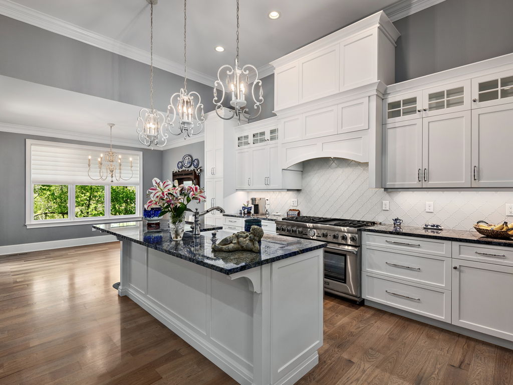 Chef's kitchen center island with custom white cabinetry and designer pendant lights