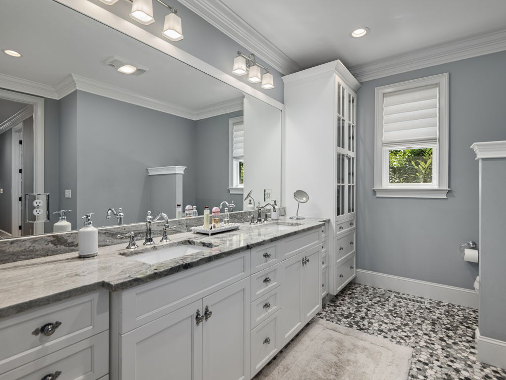 Primary bathroom dual vanity with designer mirrors, tile floor and ample storage