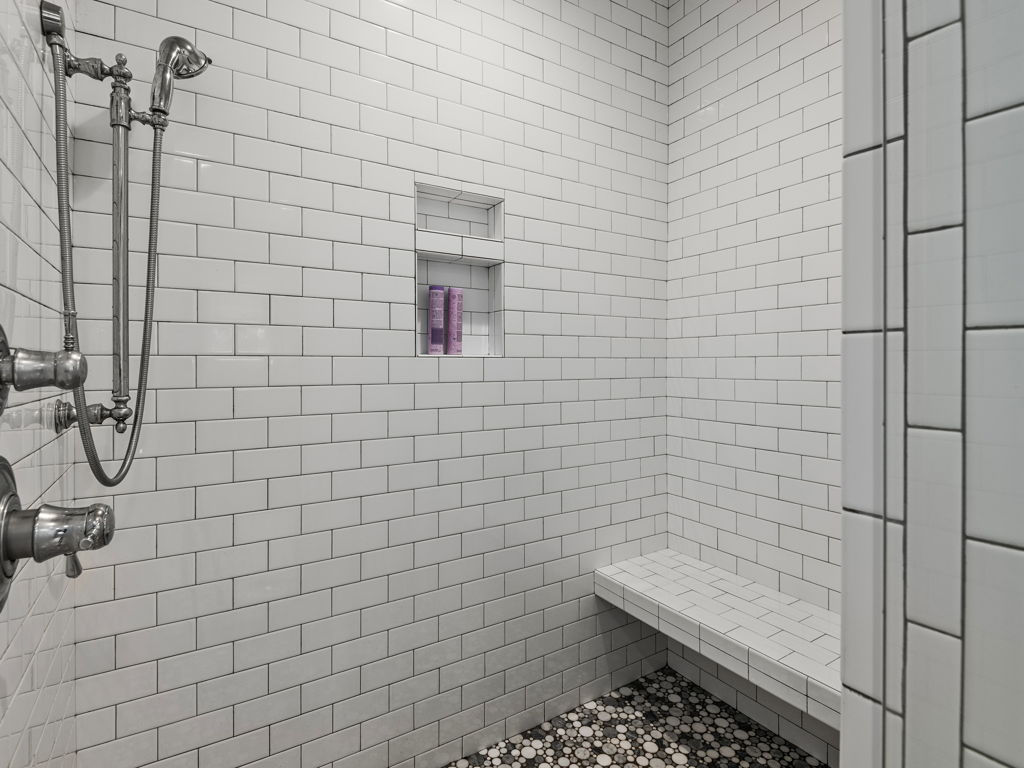 Frameless walk-in tiled shower with rain head and built-in bench seating