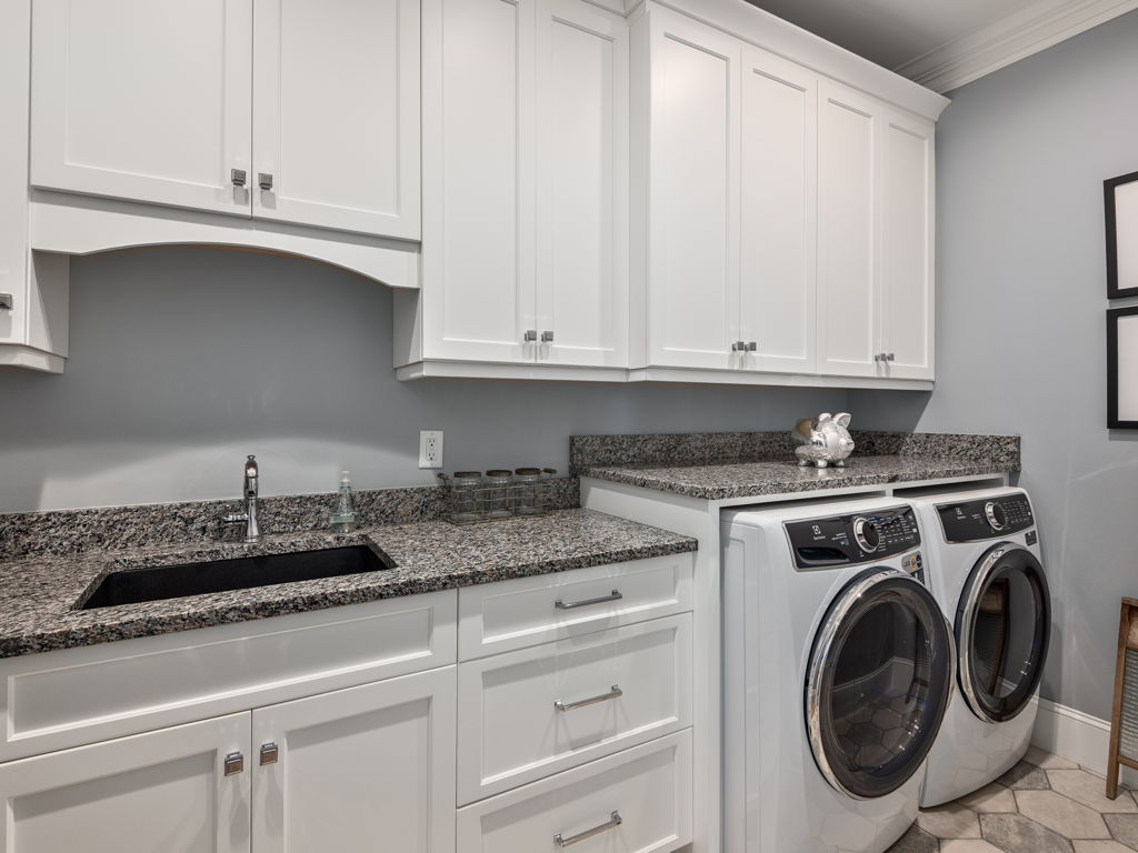 Spacious laundry room with white cabinetry, utility sink and washer dryer included