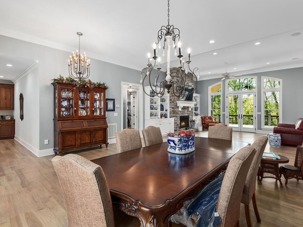 Dining area bordered by windows and walkout glass doors overlooking peaceful woods
